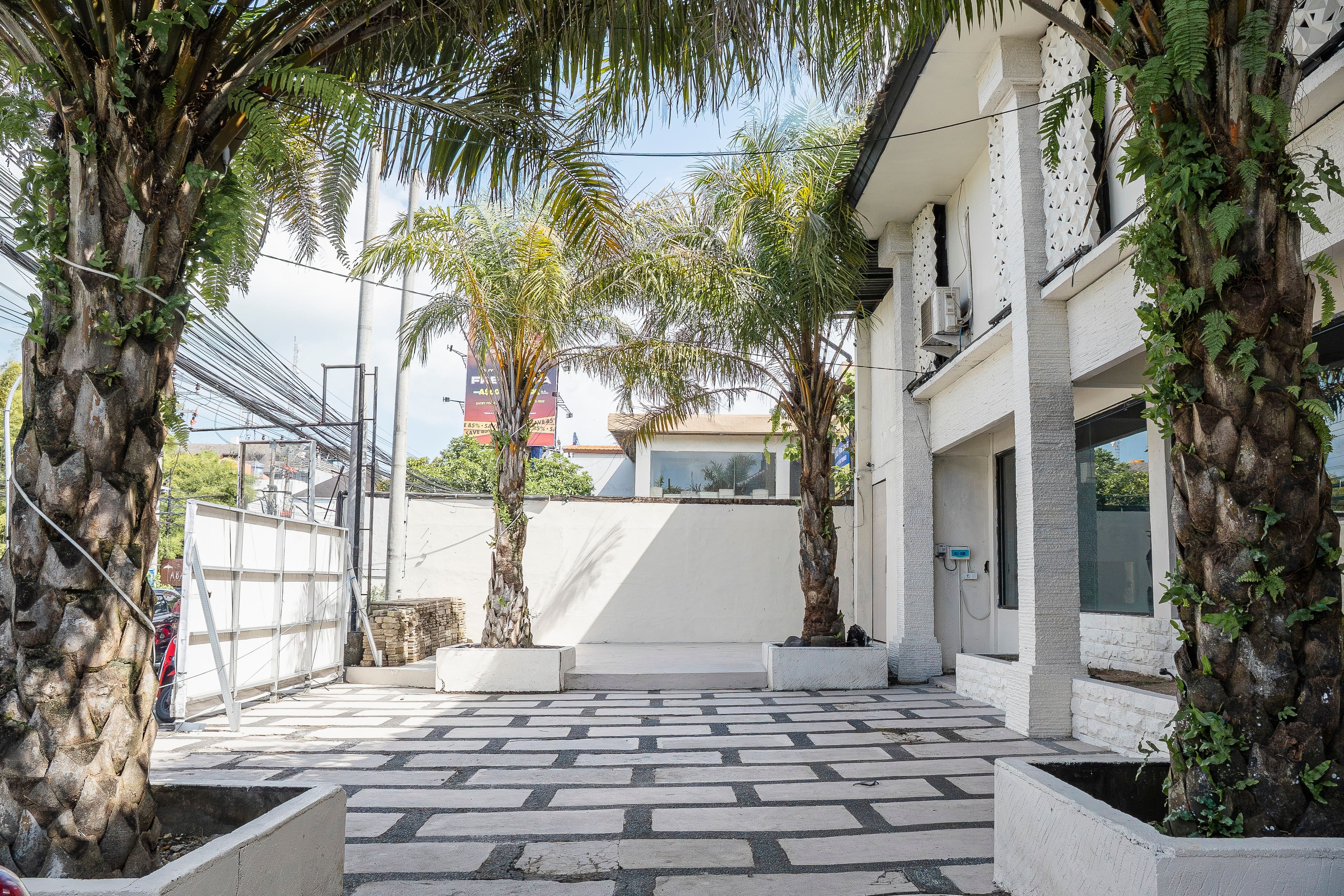 Outdoor courtyard entrance with palm trees and checkered tile pathway