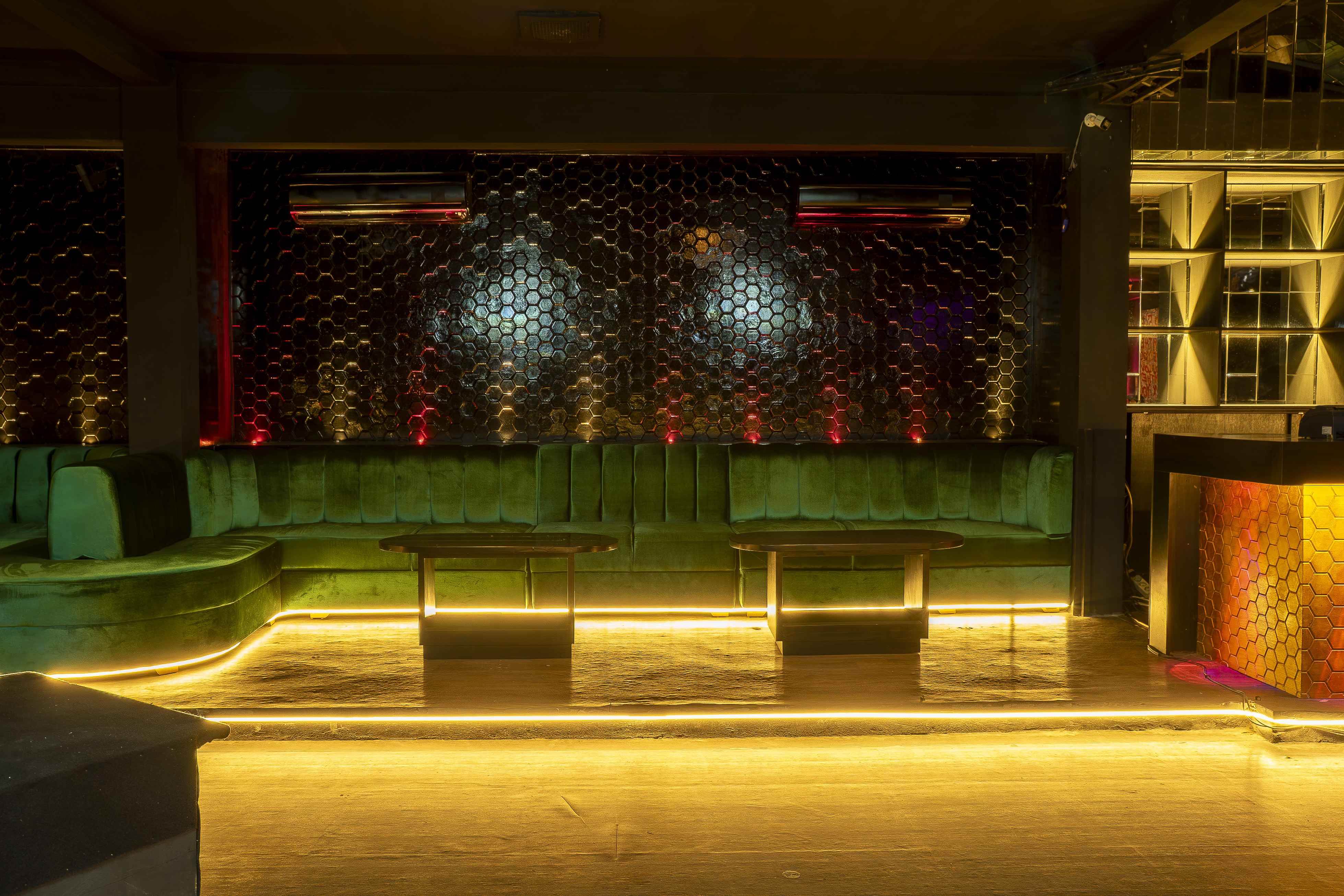 VIP seating with green velvet sofas and honeycomb wall
