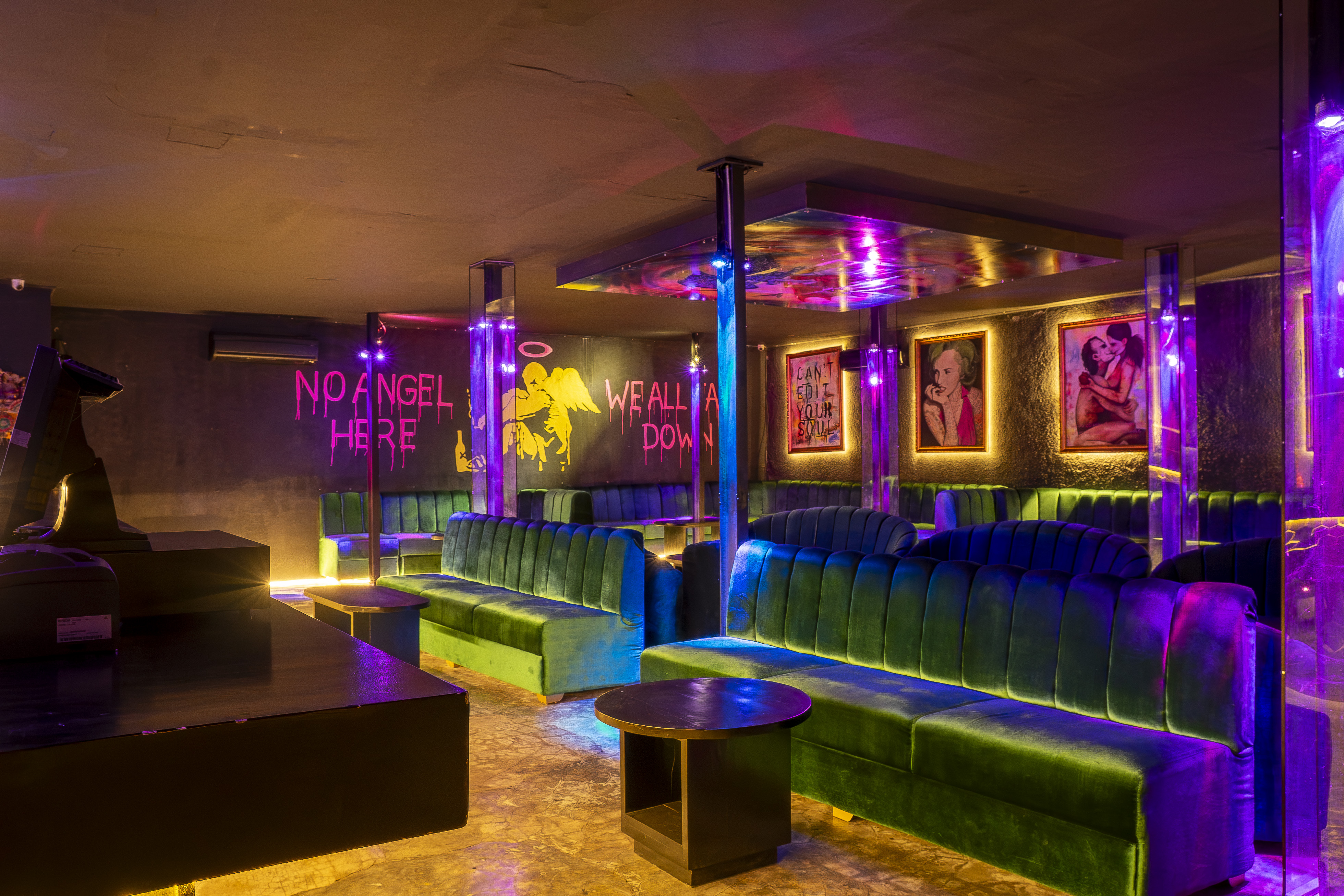 Nightclub interior with green velvet seating and neon artwork