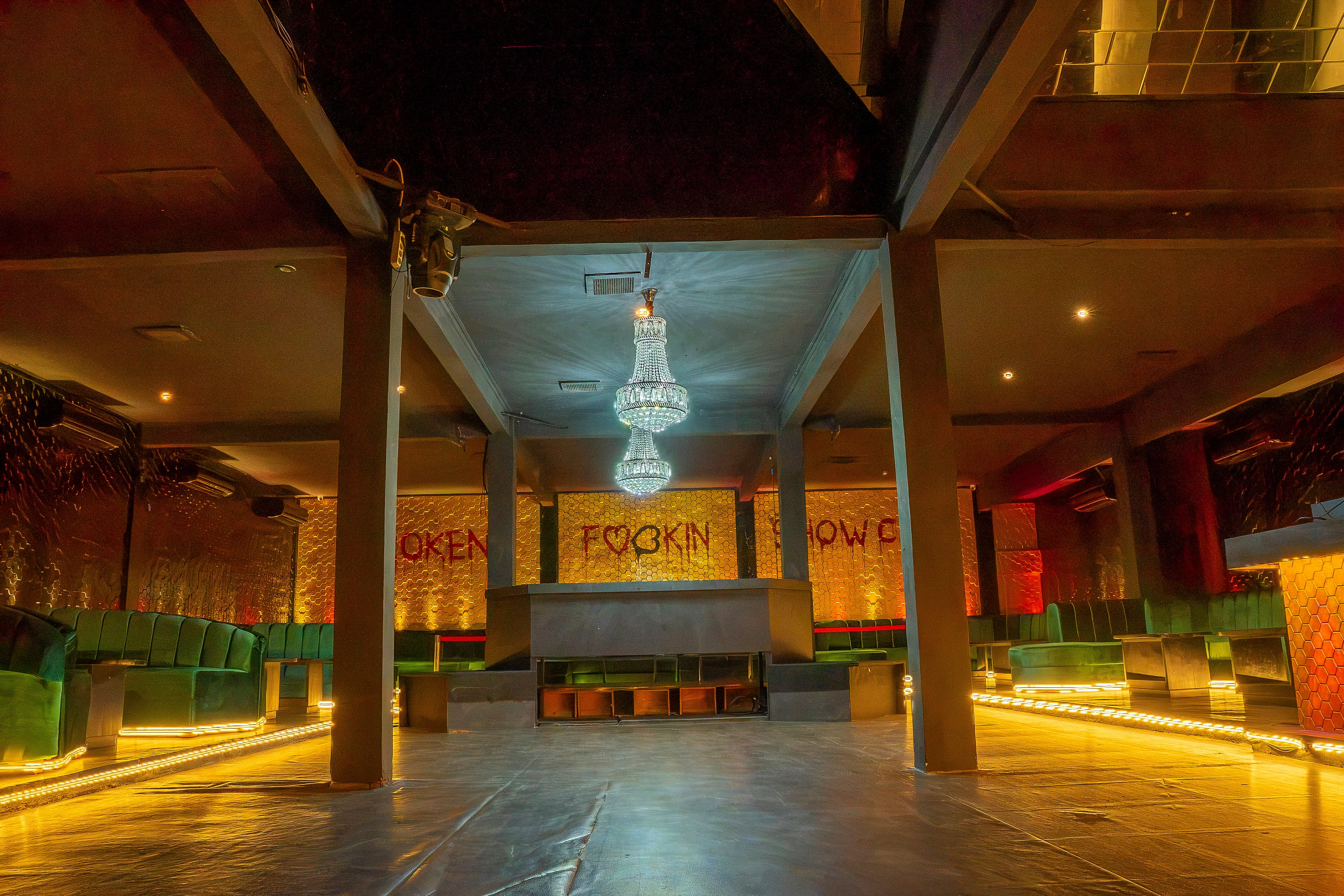 Wide shot showing chandelier and FUCKIN neon text